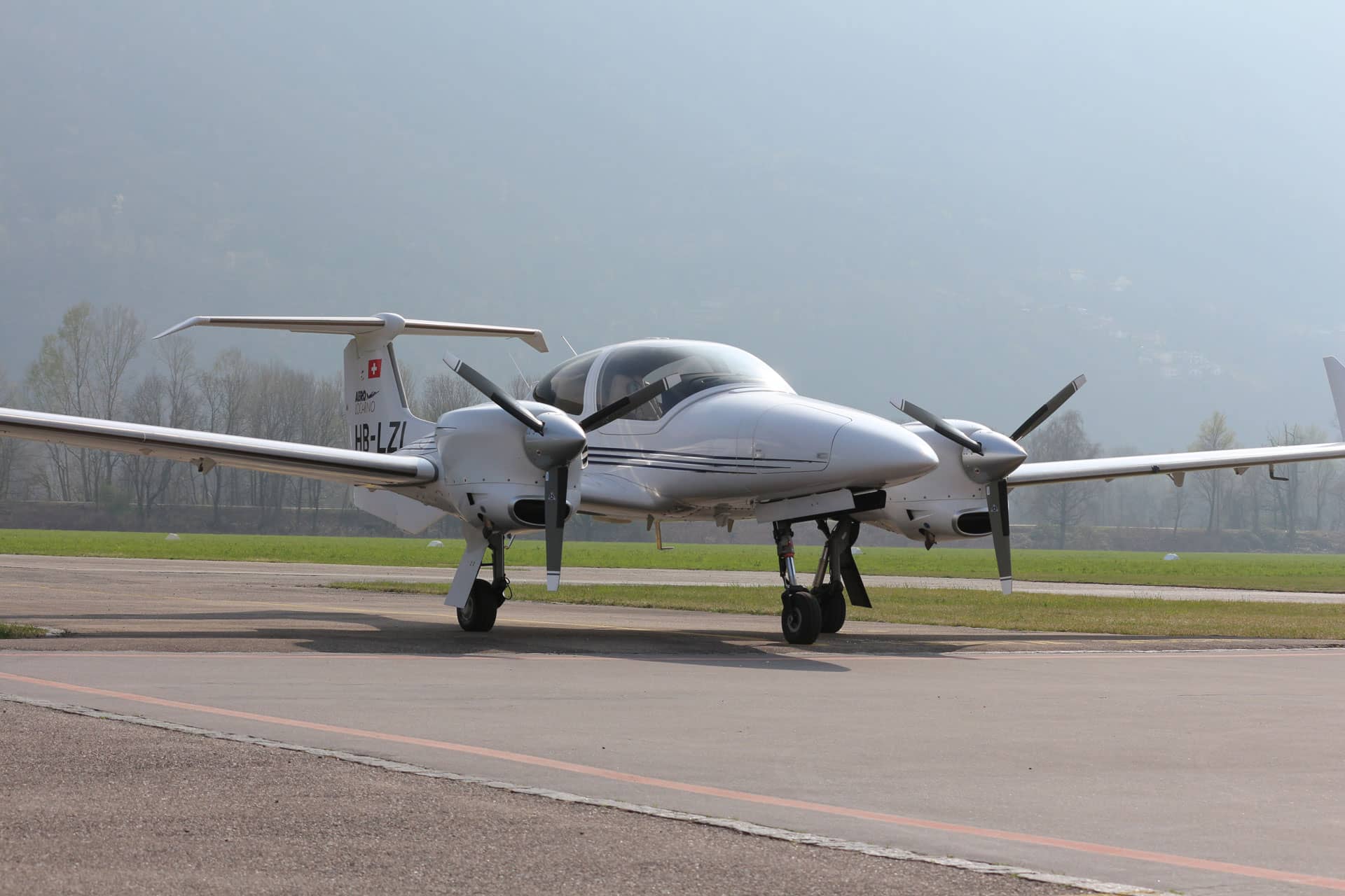 Diamond DA42 twin-engine aircraft of Aelo Swiss Academy, parked on the tarmac.