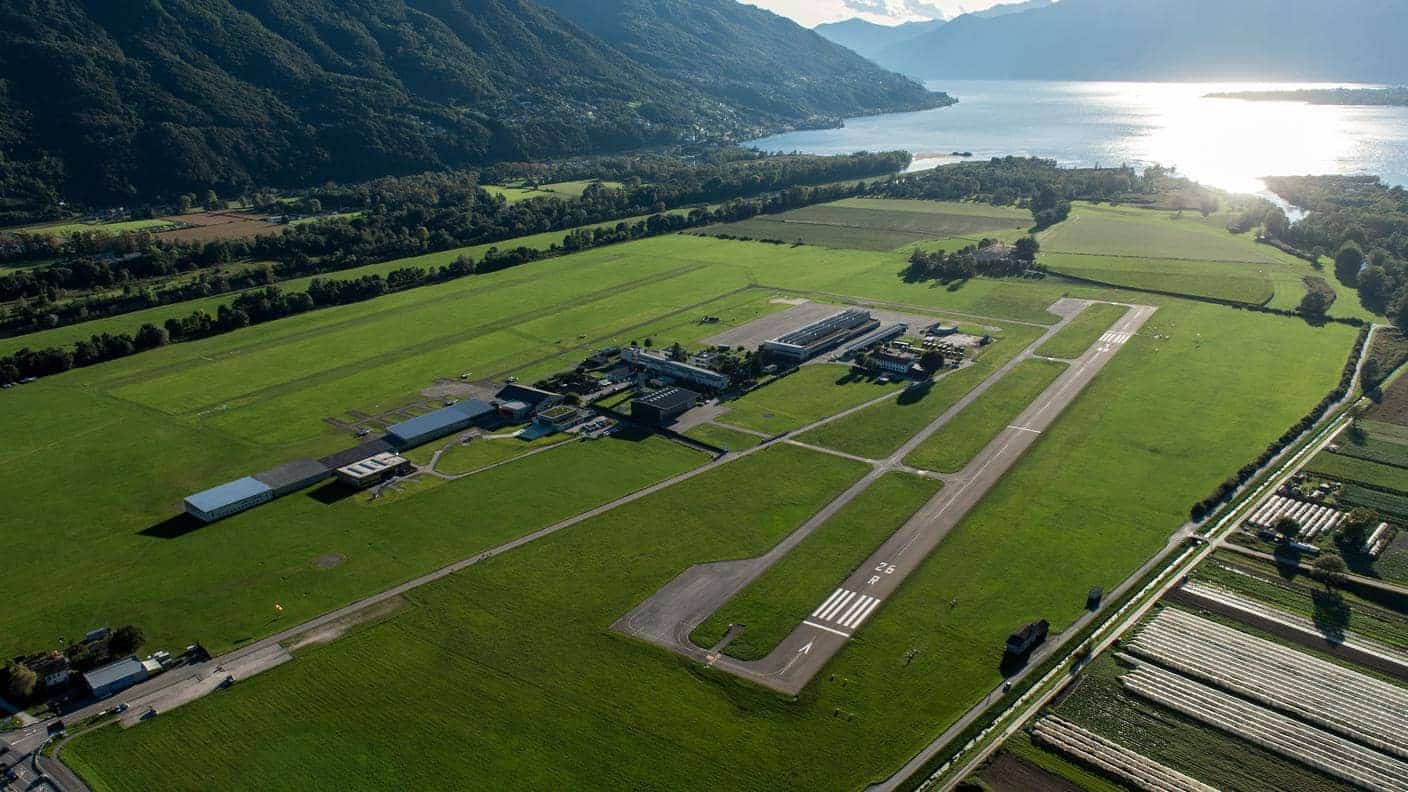 Vista aérea de Locarno Airport, base principal de Aelo Swiss Academy, con los Alpes y el lago de fondo.