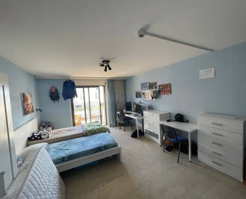 Habitación de residencia estudiantil en Locarno, Suiza, con escritorio y vistas al lago.