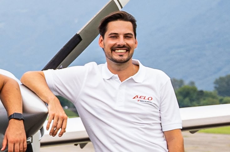 Douwe, estudiante de Aelo Swiss Academy, sonriendo junto a un avión en Suiza.