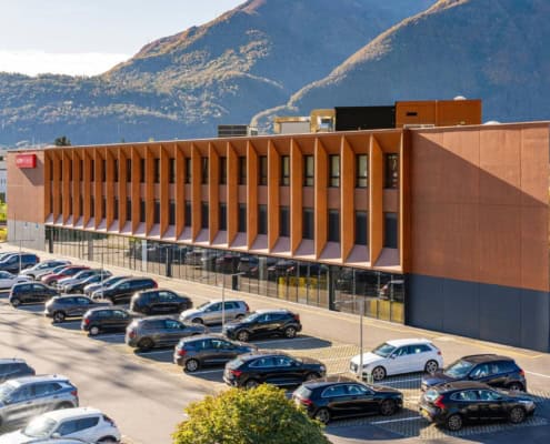 Residencia de estudiantes de Aelo Swiss Academy en Locarno, Suiza, con vista al lago y aparcamiento.