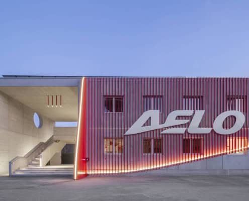 Edificio moderno de Aelo Swiss Academy con iluminación roja y logotipo visible, instalaciones de entrenamiento de pilotos.