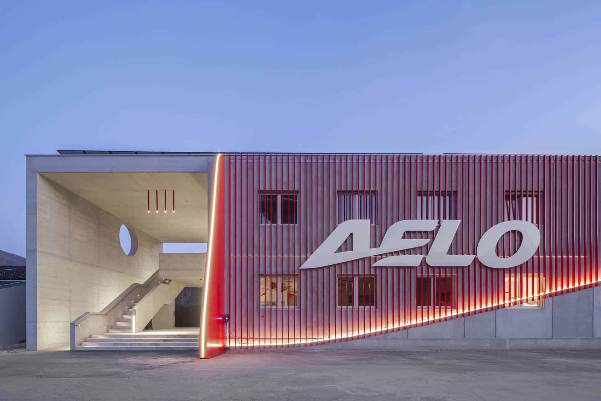 Edificio moderno de Aelo Swiss Academy con iluminación roja y logo visible, sede en el aeropuerto de Locarno.