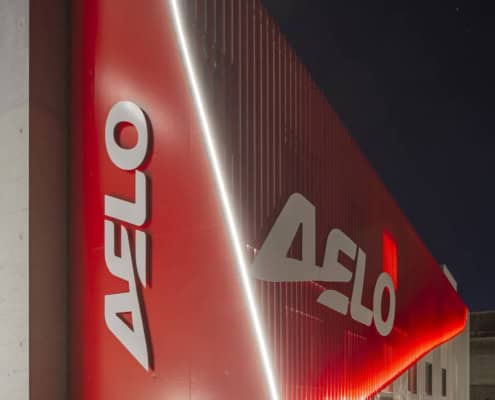Fachada iluminada con el logo de Aelo Swiss Academy, sede en Locarno Airport.