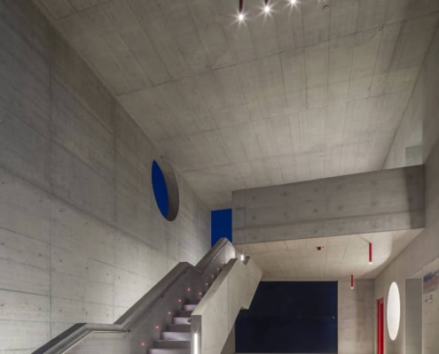 Interior moderno de la academia Aelo Swiss con escaleras y diseño arquitectónico innovador.