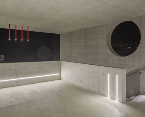 Interior moderno de la academia Aelo Swiss con iluminación y arquitectura de hormigón.